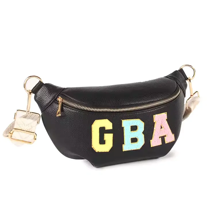 A black custom belt bag made of textured leather with a gold zipper and bold, colorful “GBA” patch letters on the front. The bag includes a detachable wide strap with gold-tone hardware, offering a trendy hands-free style.