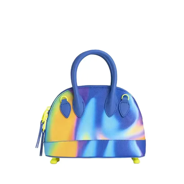 A small, dome-shaped custom handbag with a vivid, multicolor tie-dye design in blue, yellow, and purple tones. The bag includes rounded top handles and a structured silhouette, offering a bold, artistic fashion statement.