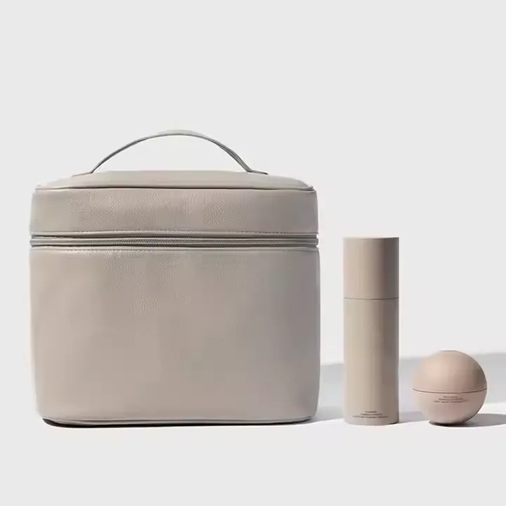 A sophisticated custom makeup bag in a smooth beige finish, presented alongside two matching minimalist cosmetic containers. The bag features a top handle and a zipper closure, designed for travel or everyday beauty organization.