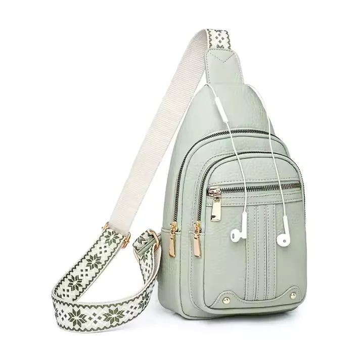 A sleek light green custom sling bag with a stylish patterned strap and multiple zippered compartments. The bag includes a headphone port, gold hardware, and a compact, vertical design ideal for everyday crossbody use.