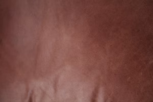 Full-grain brown leather texture close-up showing natural grain and surface character