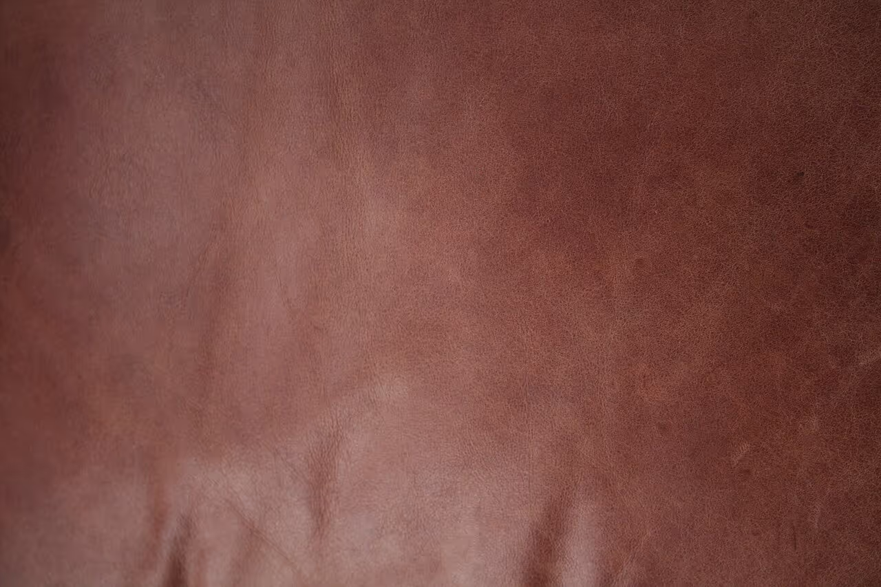 Full-grain brown leather texture close-up showing natural grain and surface character